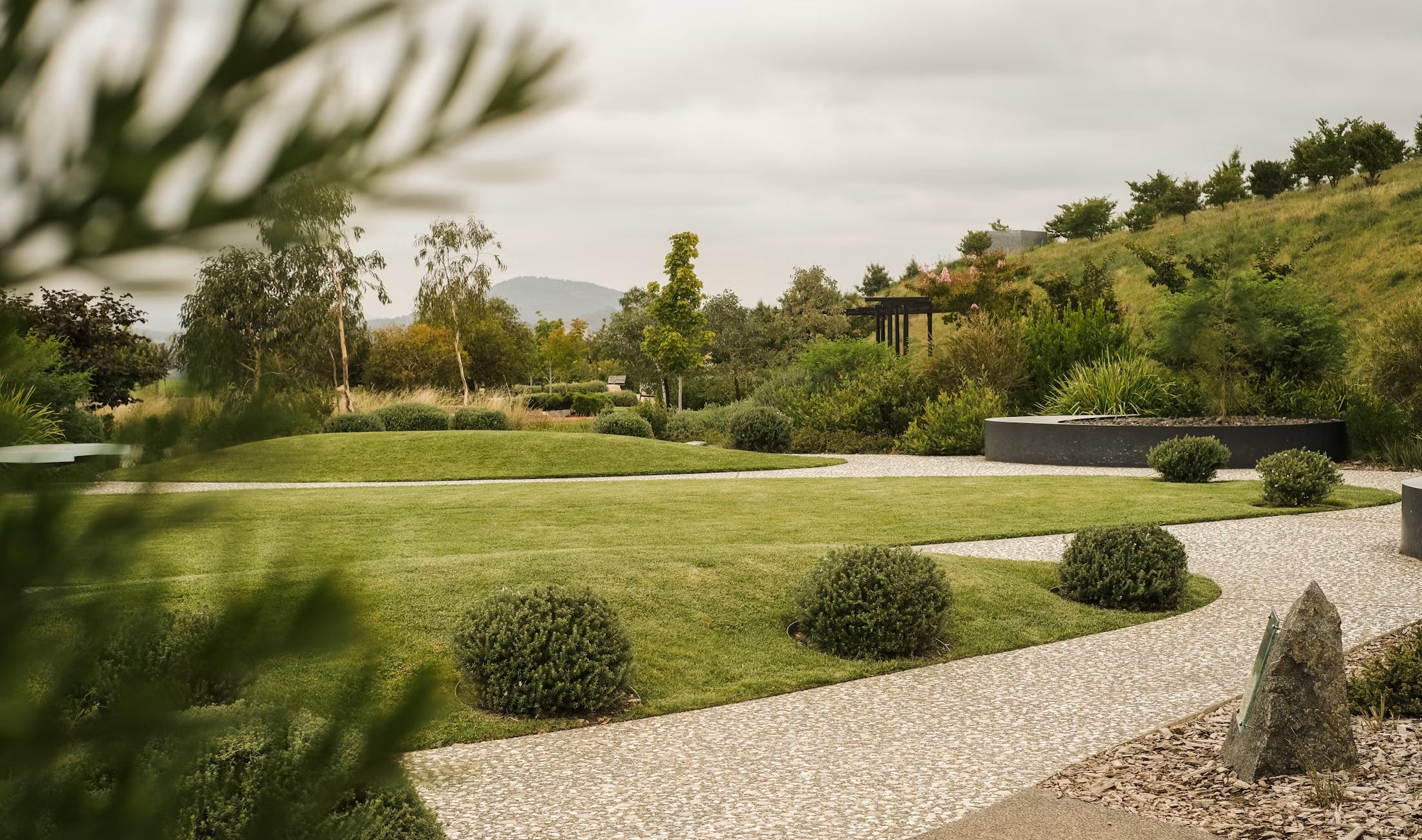 Manicured landscape with stone paths, clipped greenery, and sculpted planting beds